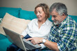 © EDER - retired couple pointing at laptop screen sitting on sofa