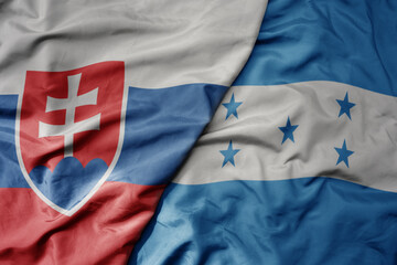big waving national colorful flag of honduras and national flag of slovakia .