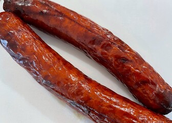 Wall Mural - Two long smoked and grilled sausages on a white background