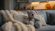 Cozy teddy bear sitting on soft sofa surrounded by knitted cushions in homely interior