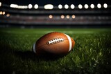 Fototapeta Sport - closeup of an American football ball on the grass of a stadium at night about to start a game - copyspace