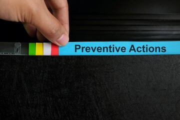 Hand picking preventive action file organizer in black background. Audit findings and root cause analysis concept.