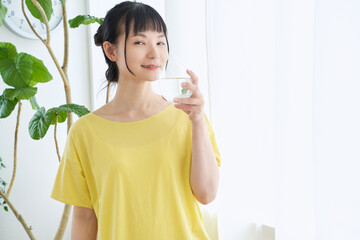 窓辺で水を飲む女性