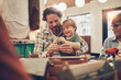 © Flamingo Images - Loving father sitting with his smiling little son sitting on his lap and bonding over family arts and crafts activities at the weekend
