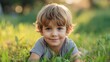 © Nemanja - Closeup of a beautiful little boy lying in the grass, looking at the camera and smiling. Summer outdoor leisure time and relaxation for a young male kid, carefree toddler or preschooler