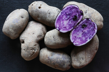 Wall Mural - Vitelotte potatoes on slate background for food illustrations