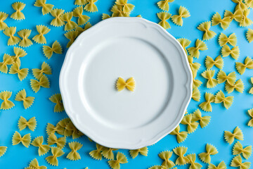 Wall Mural - Raw pasta farfalle with copy space on blue background