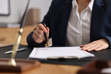 Poster - Notary sealing document at table in office, closeup