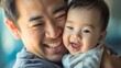 © Nemanja - Asian father and his cute little baby son, man standing indoors with his male child or kid, both of them are smiling and looking at the camera. Home relaxation, happy family, fatherhood concept