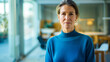 © ReaverCrest - European businesswoman wearing a blue sweater standing in her home office