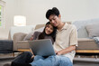 © Natee Meepian - Happy couple asian with laptop on floor in the living room at home