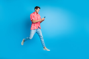 Sticker - Full body photo of busy guy wear stylish shirt jeans trousers run empty space read sms on smartphone isolated on blue color background