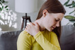 © Yura Yarema - Pain body muscles stiff problem. Close up of upset young caucasian female holding neck ache from work, sad girl massaging rubbing shoulder hurt, sore sitting alone on sofa at home. Health care concept