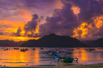 Wall Mural - A group of colorful boats docked on a calm lake at sunset, with mountains and clouds in the background.