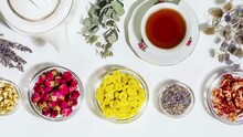 Healing Herbal Tea With Wild Plants And Flowers. Home Herbal Apothecary Concept. Sustainable Flat Lay With Natural Flowers And Herbs, Cup Of Tea, Tea Pot, Spoons On White Background