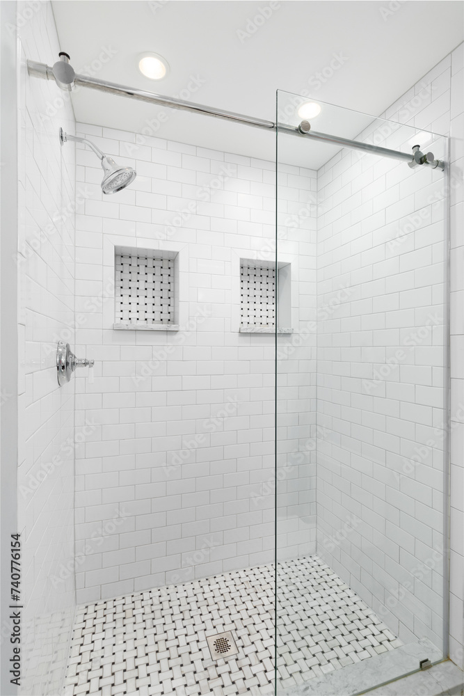 A walk-in shower with white subway tiles, sliding glass door, chrome ...