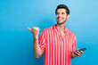 Photo of dreamy funky man dressed striped shirt texting modern device thumb empty space isolated blue color background