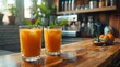 Carrot juice in glasses on wooden counter top.
