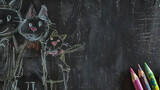 A creative chalkboard drawing featuring playful cats next to a set of brightly colored crayons on the side.
