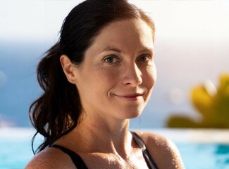 Poster - Brunette mature woman smiling in the pool of the resort hotel, with a view of the sea. On vacation.