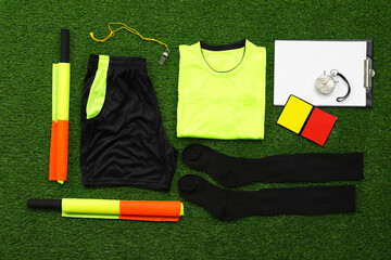 Wall Mural - Uniform and other referee equipment on green grass, flat lay