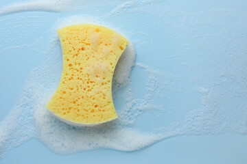 Canvas Print - Yellow sponge with foam on light blue background, top view. Space for text