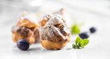 Fototapeta  - Profiterole or cream puff with filling,  powdered sugar topping with berries, isolated on white background, Fresh homemade Cream Puffs, cake, tasty French choux puff, ecler, dessert closeup. Pastries