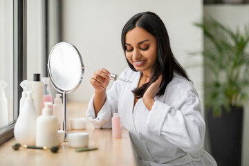 Wall Mural - Beautiful millennial indian woman using hair oil