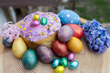 multi-colored Easter eggs, homemade Easter cake decorated with chocolate eggs in foil and a large hyacinth flower. Easter concept. Christ is risen. Orthodox holiday