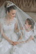 © Vasil - Portrait of the bride with her little sister in the room. Tender and sweet photo of a beautiful bride with her little sister.
