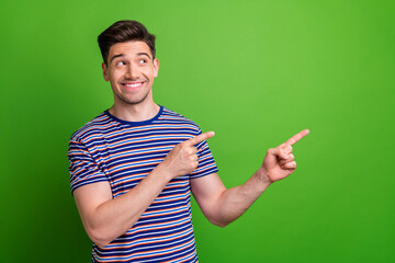 Wall Mural - Photo of cheerful person toothy smile look indicate fingers empty space information isolated on green color background