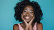 © MP Studio - young woman with a joyful expression, her hands gently touching her face, against a turquoise background.