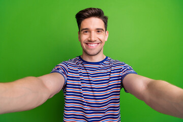 Canvas Print - Portrait of optimistic handsome cheerful man with bristle wear stylish t-shirt making selfie smiling isolated on green color background