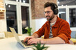 © zinkevych - Young dark-haired man in headphones working on laptop