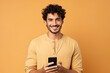 © AI_images - Happy Latin American man with phone on Beige studio background