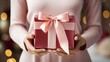 © olegganko - two white hands holding a pink gift box with gold ribbon