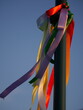 Colored silk ribbons flutter on a street lighting pole in the rays of the sun
