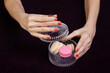 close-up of caucasian female hand holding with fingers a delicious sweet bright pink macaron. Tasty dessert