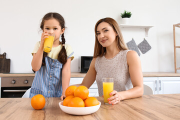 Canvas Print - Little girl with her mother drinking orange juice in kitchen