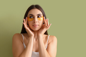 Wall Mural - Pretty young woman with under-eye patches on green background