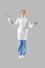 Canvas Print - Female doctor with clipboard and enema jumping on light background