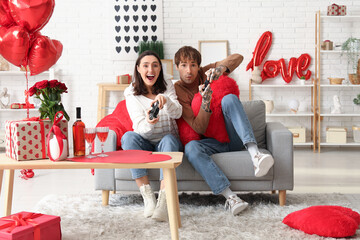 Wall Mural - Young couple playing video games at home. Valentine's day celebration