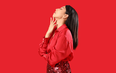 Wall Mural - Beautiful young Asian woman in stylish outfit on red background