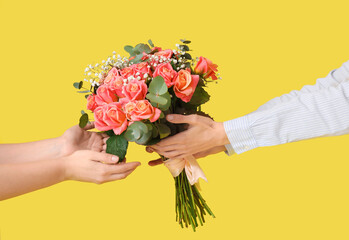 Woman receiving bouquet of beautiful flowers on yellow background