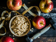 Healthy eating and dieting concept. Oatmeal, apples and dumbbells on wooden background