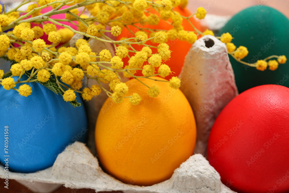 Paper holder with painted Easter eggs and mimosa flowers, closeup