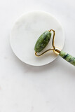 Fototapeta Mapy - Green jade roller massager for face on white marble.