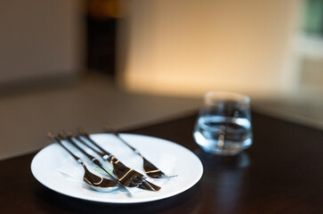 Simple dining table, table setting, glasses, metal cutlery, white ceramic plates, platters, simple style restaurant decoration, green management, environmentally friendly enterprise