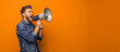A man shouting through megaphone portrait in the studio orange background.

