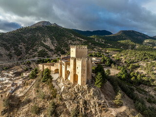 Canvas Print - Aerial view of Velez Blanco hilltop medieval castle with square tower, restored Gothic palace above the town with dramatic sky